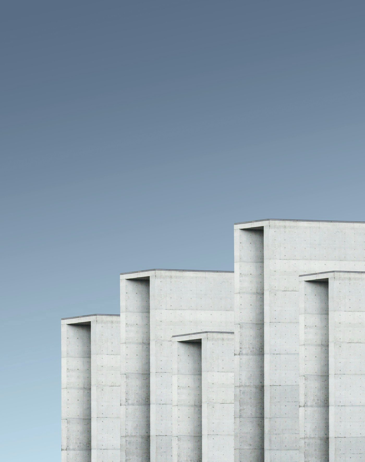 Rhythmic concrete facade of a modern building against a pale sky